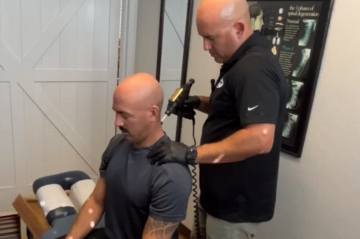 Dr. Aranibar using a tool on a patient's neck and shoulders